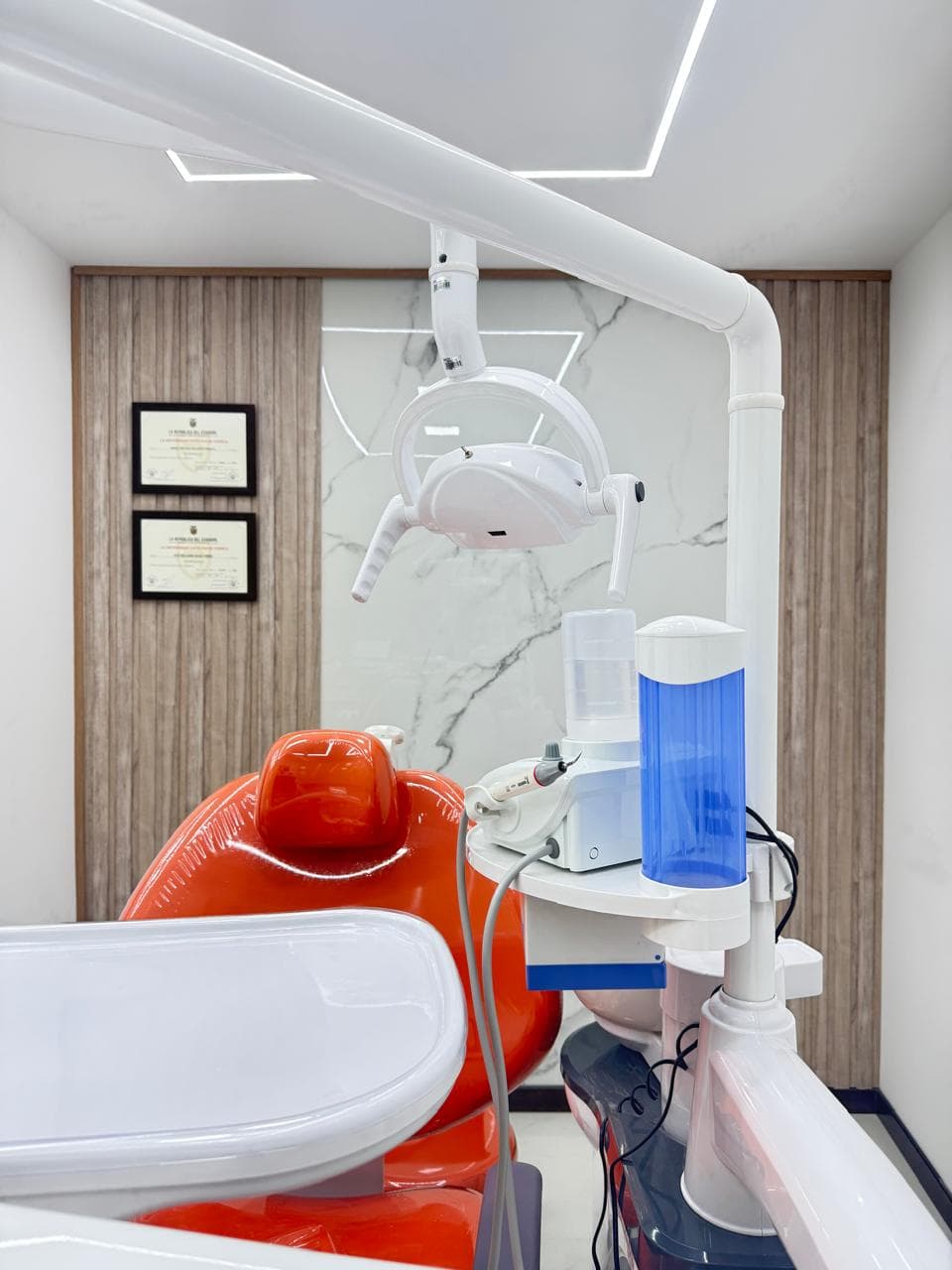 Modern dental office featuring a bright orange chair, overhead light, and professional medical equipment.