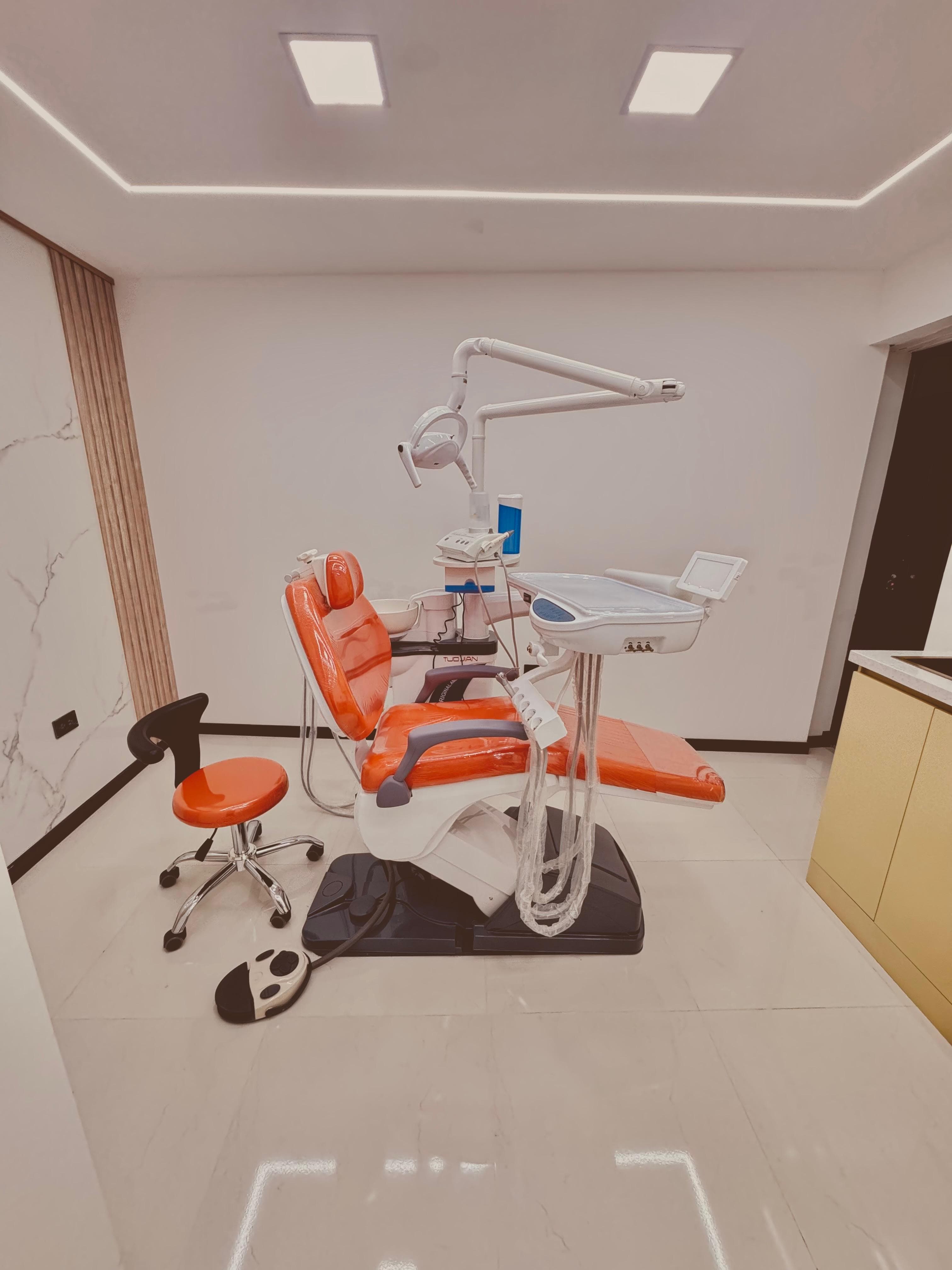 Bright orange dental chair and professional medical equipment in a minimalist, well-lit clinic setting.